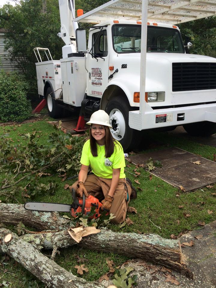 The girl with white hat holding a chainsaw.